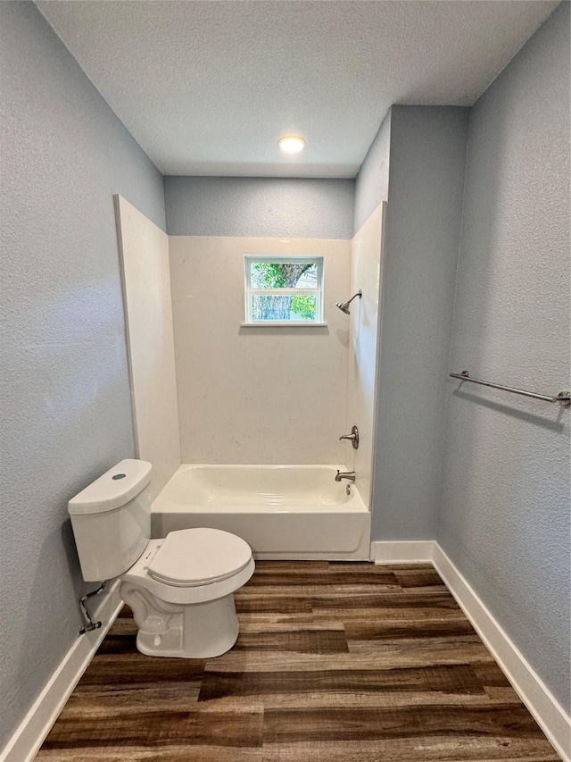 full bathroom featuring a textured ceiling, toilet, shower / bath combination, wood finished floors, and baseboards