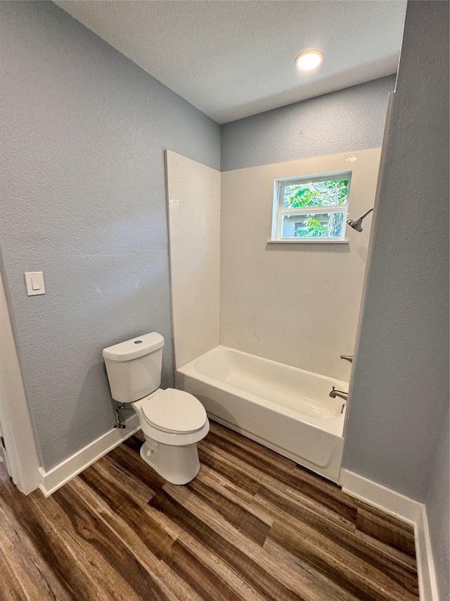 bathroom featuring baseboards, a textured wall, toilet, and wood finished floors