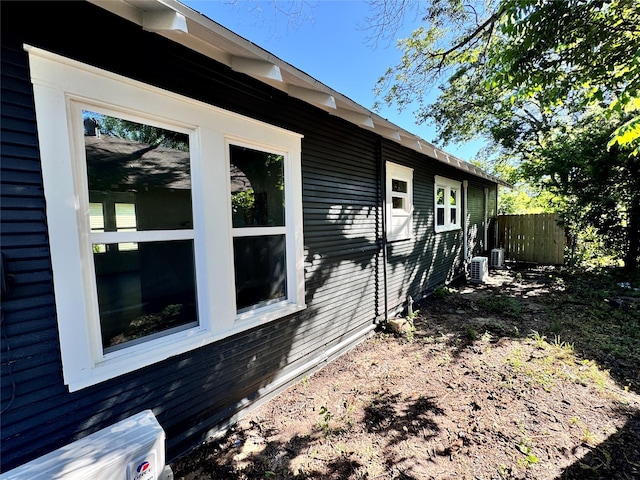 view of side of property with central AC and fence