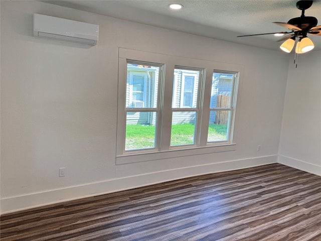 spare room with recessed lighting, dark wood-type flooring, a textured ceiling, a wall mounted air conditioner, and baseboards