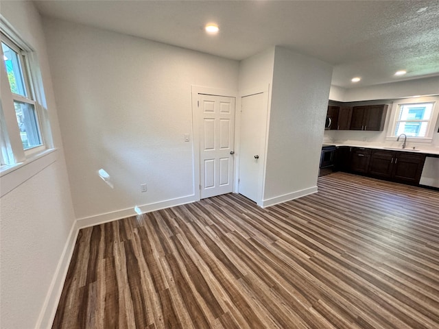 interior space with wood finished floors, recessed lighting, a sink, and baseboards