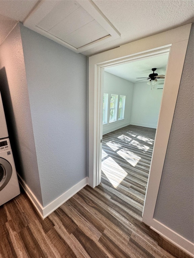 interior space featuring laundry area, baseboards, stacked washer and dryer, and dark wood finished floors