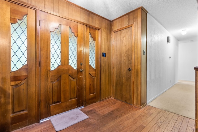 entrance foyer with wood walls, hardwood / wood-style floors, and a textured ceiling