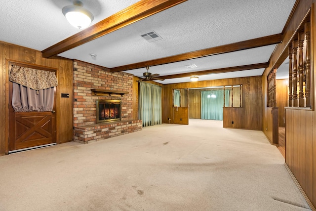 unfurnished living room with light carpet, beam ceiling, a textured ceiling, and wood walls