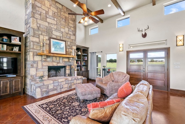 tiled living room with a high ceiling, beamed ceiling, ceiling fan, and a stone fireplace