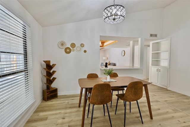 dining area with light hardwood / wood-style floors and an inviting chandelier