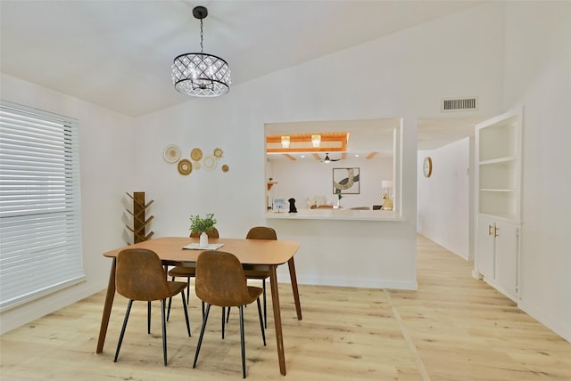 dining room featuring vaulted ceiling, light hardwood / wood-style flooring, and a notable chandelier