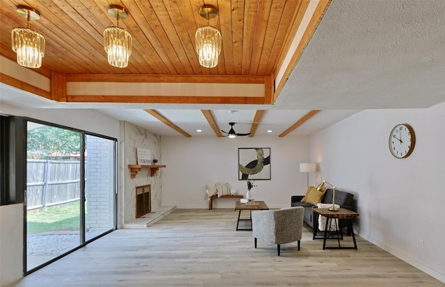 sitting room with light hardwood / wood-style floors, a stone fireplace, and wooden ceiling