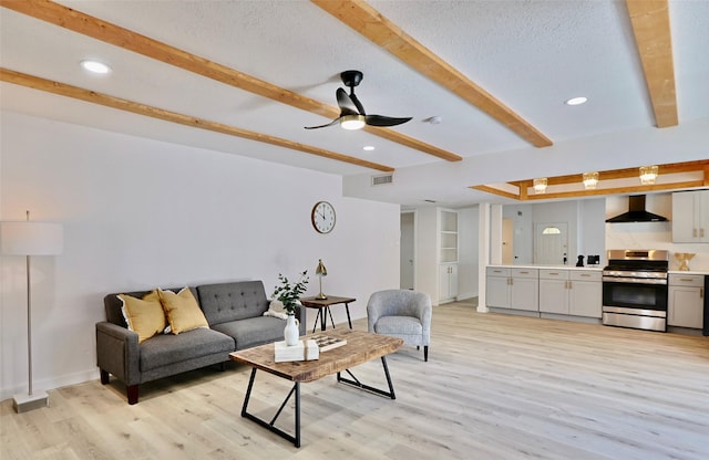 living room with beamed ceiling, a textured ceiling, light hardwood / wood-style floors, and ceiling fan