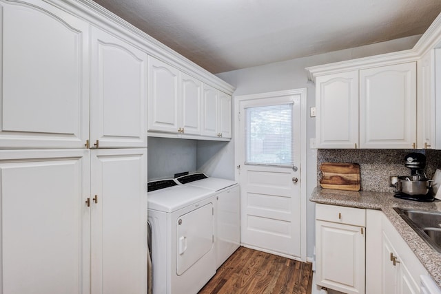 laundry room with washing machine and clothes dryer, dark hardwood / wood-style flooring, cabinets, and sink