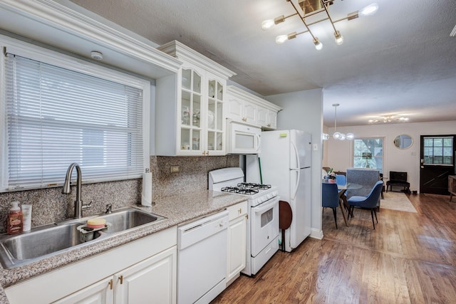 kitchen featuring white appliances, sink, dark hardwood / wood-style floors, white cabinetry, and hanging light fixtures