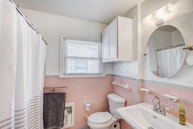 bathroom featuring toilet, tile walls, and sink