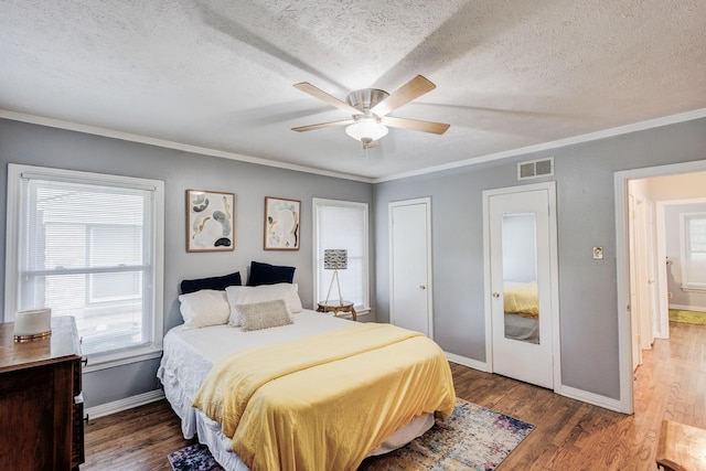 bedroom with a textured ceiling, dark hardwood / wood-style flooring, ceiling fan, and crown molding