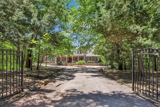 view of front of home with gravel driveway, a gate, and brick siding