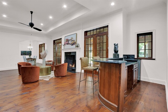 kitchen with dark hardwood / wood-style flooring, a high end fireplace, a raised ceiling, and ceiling fan with notable chandelier