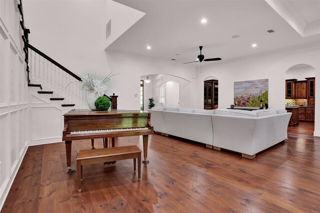 living room with crown molding, dark hardwood / wood-style floors, and ceiling fan