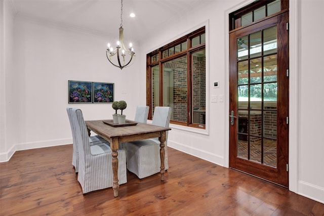 dining room featuring wood-type flooring, crown molding, baseboards, and an inviting chandelier