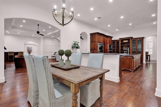 dining area with arched walkways, crown molding, recessed lighting, dark wood-type flooring, and ceiling fan with notable chandelier