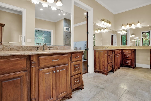 bathroom with ornamental molding, stone finish flooring, two vanities, and a sink