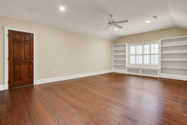 unfurnished room with built in shelves, lofted ceiling, visible vents, dark wood-type flooring, and baseboards