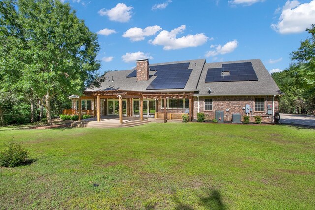 rear view of property featuring a patio, solar panels, central AC unit, a pergola, and a yard