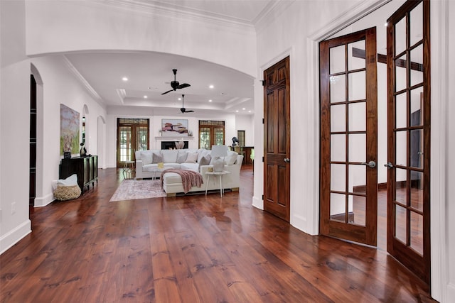 unfurnished living room with ornamental molding, a tray ceiling, dark wood finished floors, and ceiling fan