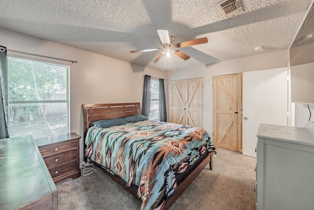 carpeted bedroom featuring ceiling fan and a textured ceiling