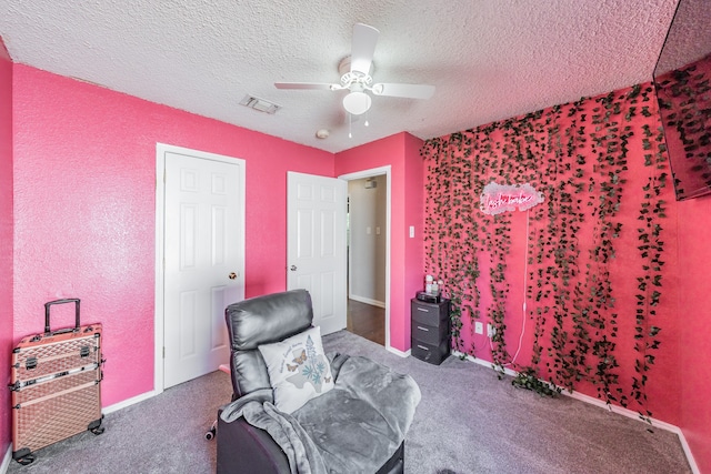 sitting room featuring a textured ceiling, carpet, and ceiling fan