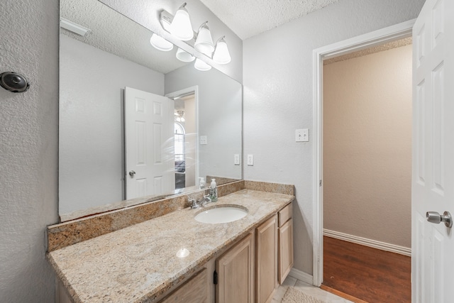 bathroom with vanity with extensive cabinet space, a textured ceiling, and hardwood / wood-style flooring