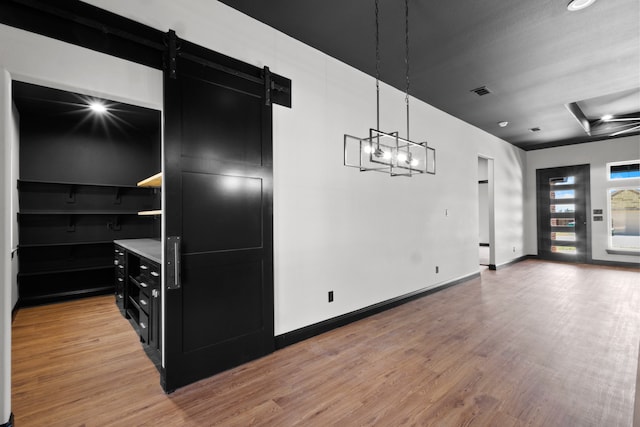 kitchen with decorative light fixtures, a barn door, and light hardwood / wood-style floors