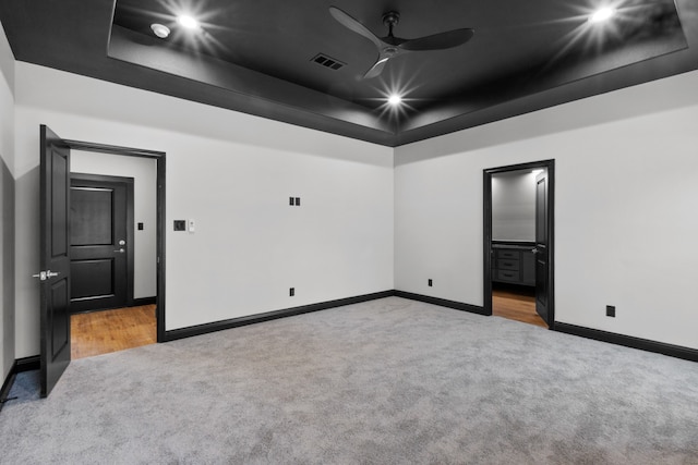 spare room featuring ceiling fan, a raised ceiling, and light carpet