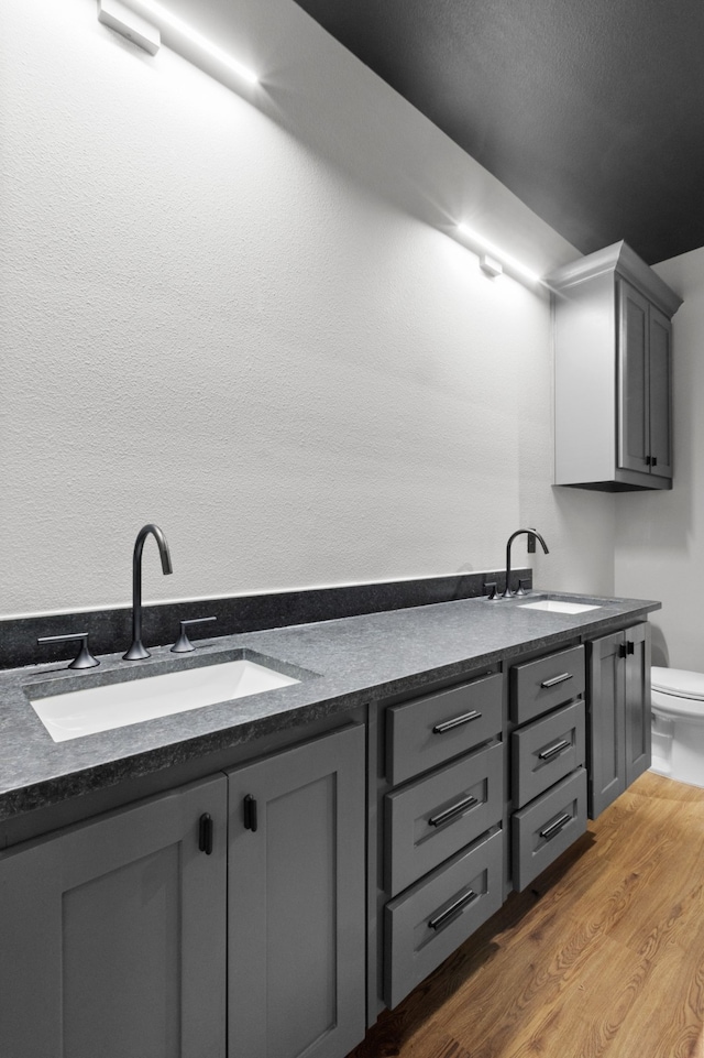 bathroom with wood-type flooring, double sink vanity, and toilet