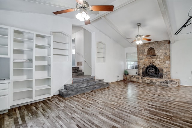 unfurnished living room with wood-type flooring, vaulted ceiling with beams, a fireplace, and ceiling fan