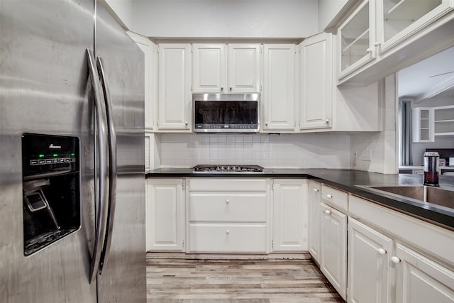 kitchen with tasteful backsplash, appliances with stainless steel finishes, light wood-type flooring, and white cabinets