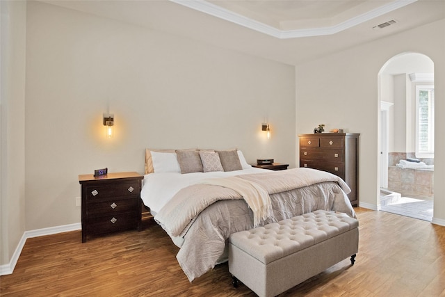 bedroom featuring wood-type flooring, ornamental molding, and connected bathroom