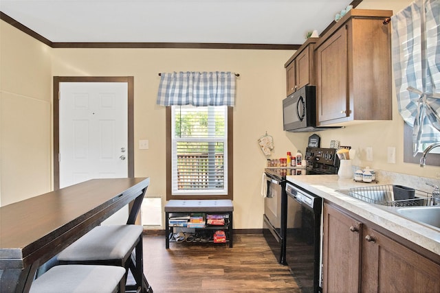 kitchen featuring crown molding, dark hardwood / wood-style flooring, black appliances, and sink