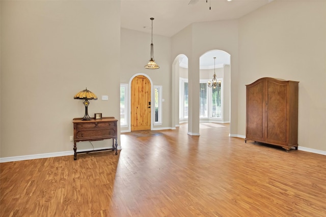 entrance foyer featuring a high ceiling, ceiling fan with notable chandelier, light hardwood / wood-style floors, and a healthy amount of sunlight