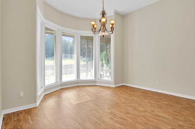 unfurnished room featuring wood-type flooring, ornamental molding, and a notable chandelier