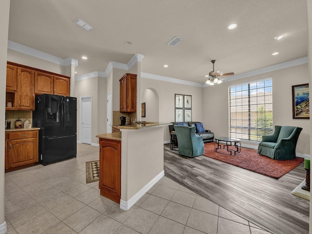 kitchen with black fridge with ice dispenser, ornamental molding, a kitchen breakfast bar, kitchen peninsula, and decorative backsplash