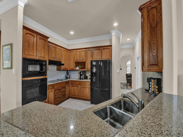 kitchen featuring light stone counters, sink, decorative backsplash, and black appliances