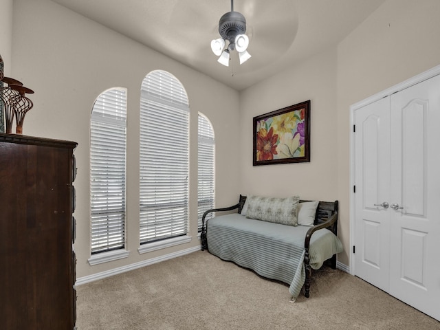 bedroom with light carpet, ceiling fan, and a closet