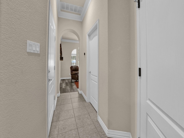 hallway featuring crown molding and light tile patterned flooring