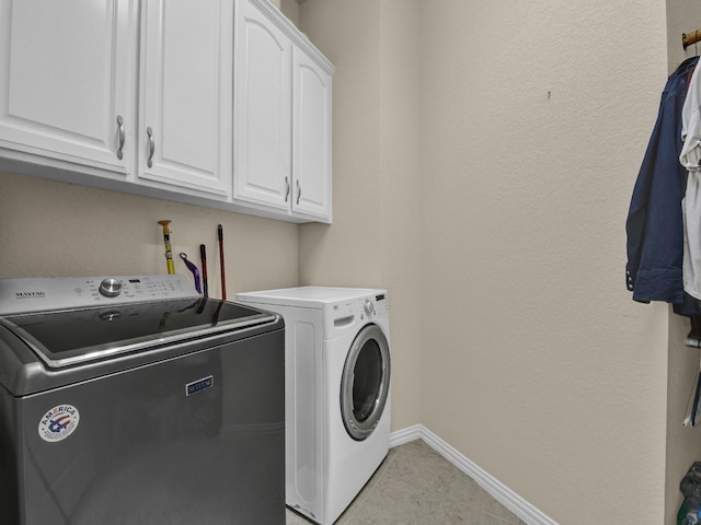 clothes washing area featuring cabinets and washing machine and dryer