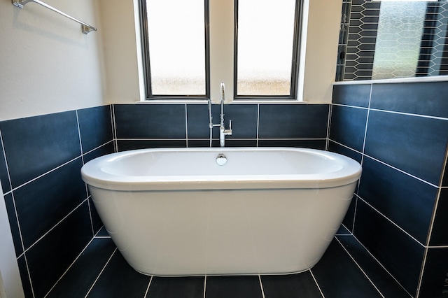 bathroom featuring tile patterned flooring, a bath, and tile walls