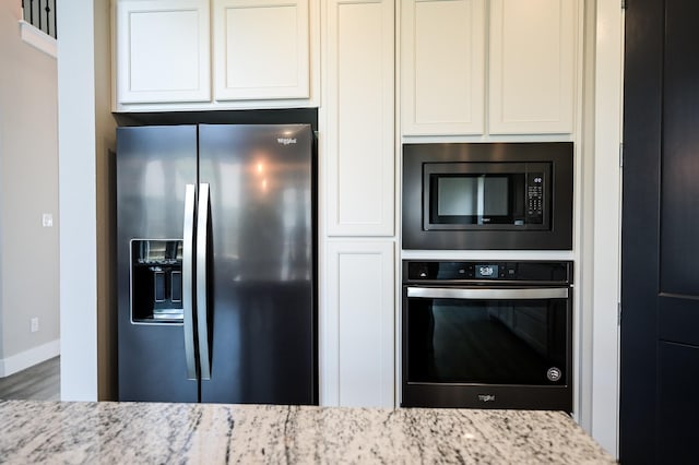 kitchen featuring stainless steel appliances, light stone countertops, hardwood / wood-style floors, and white cabinets