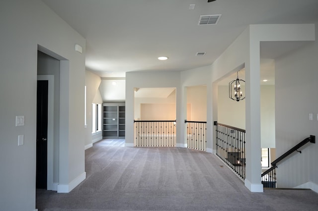 corridor with a notable chandelier and carpet flooring