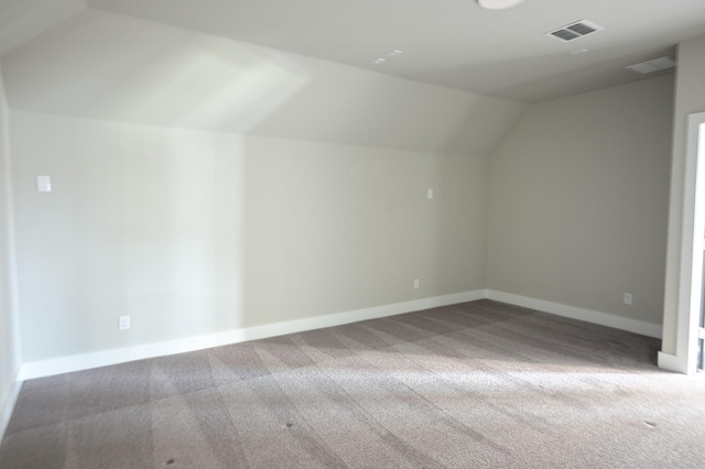 additional living space featuring vaulted ceiling and carpet flooring