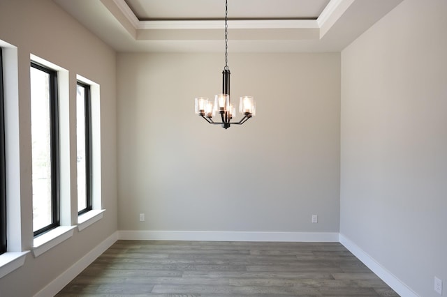 unfurnished room with an inviting chandelier, ornamental molding, wood-type flooring, and a raised ceiling