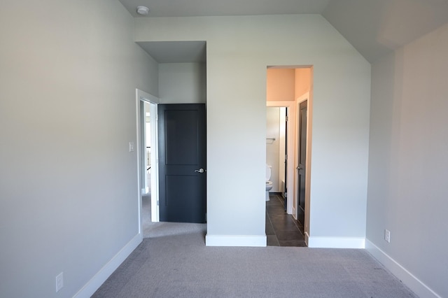 unfurnished bedroom featuring dark colored carpet and lofted ceiling