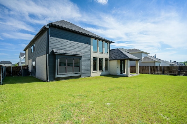 rear view of property featuring central AC and a lawn